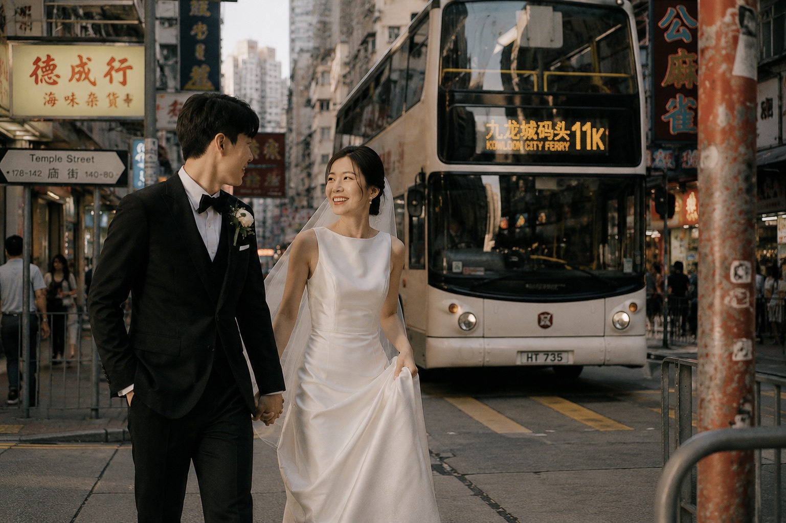 The couple walking near Temple Street with a double-decker bus behind them
