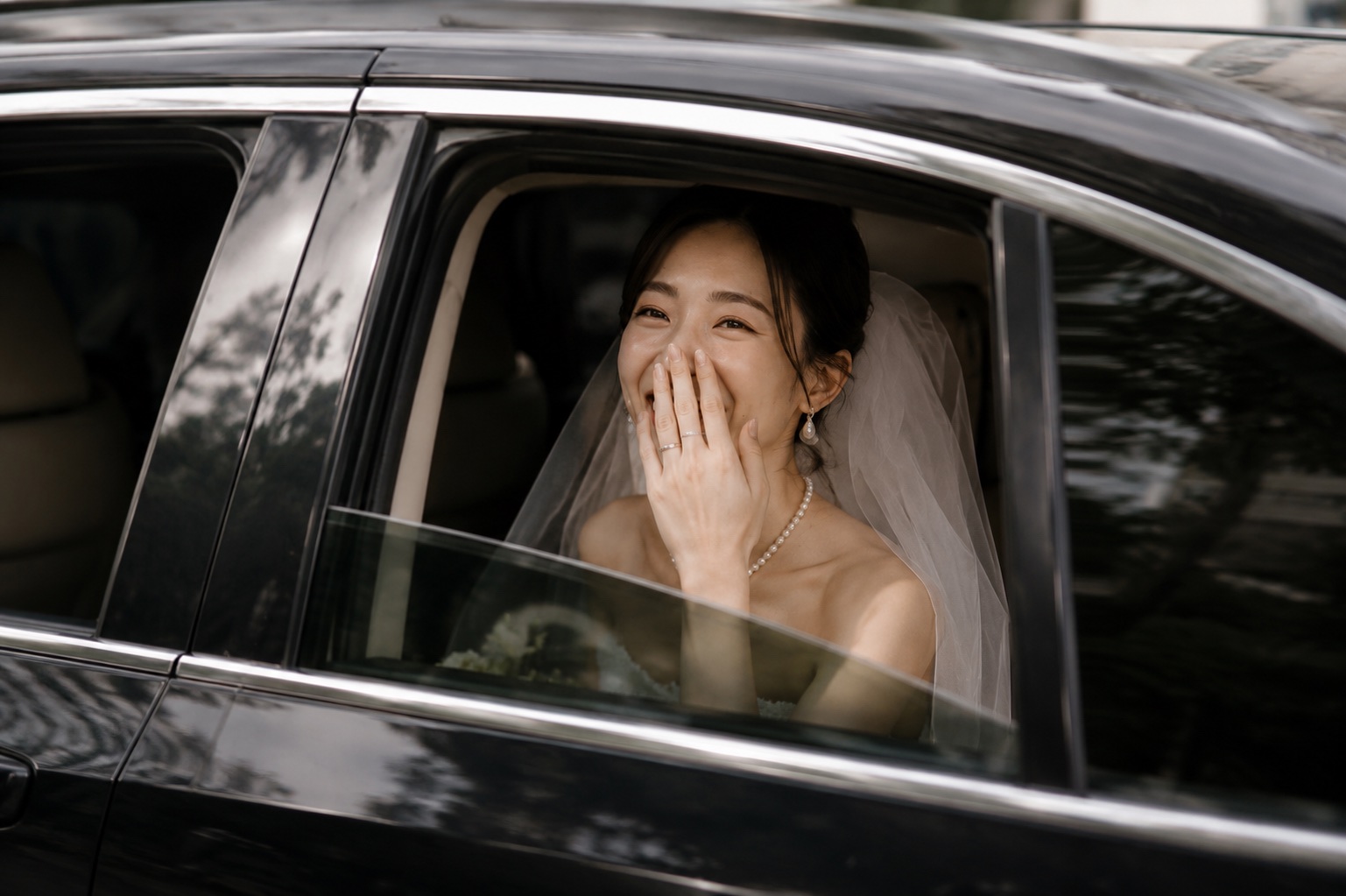 Suki smiling from the window of a black wedding car