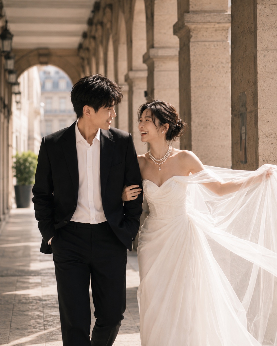 Mina and Jules smiling at one another while walking through a colonnade